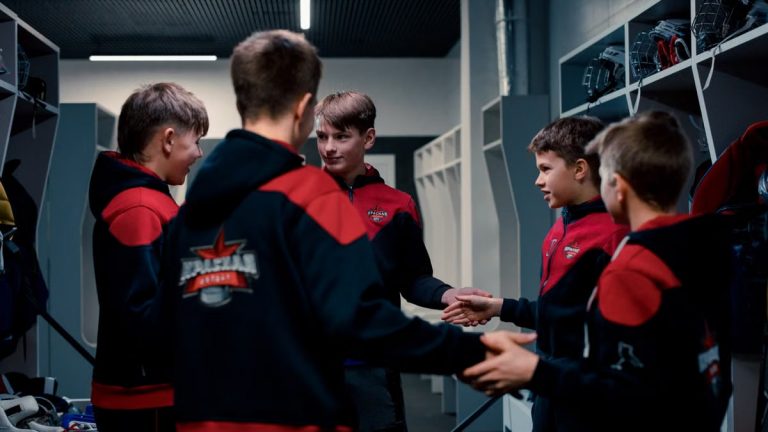 A group of teenage boys in a locker room displaying team spirit before a game.