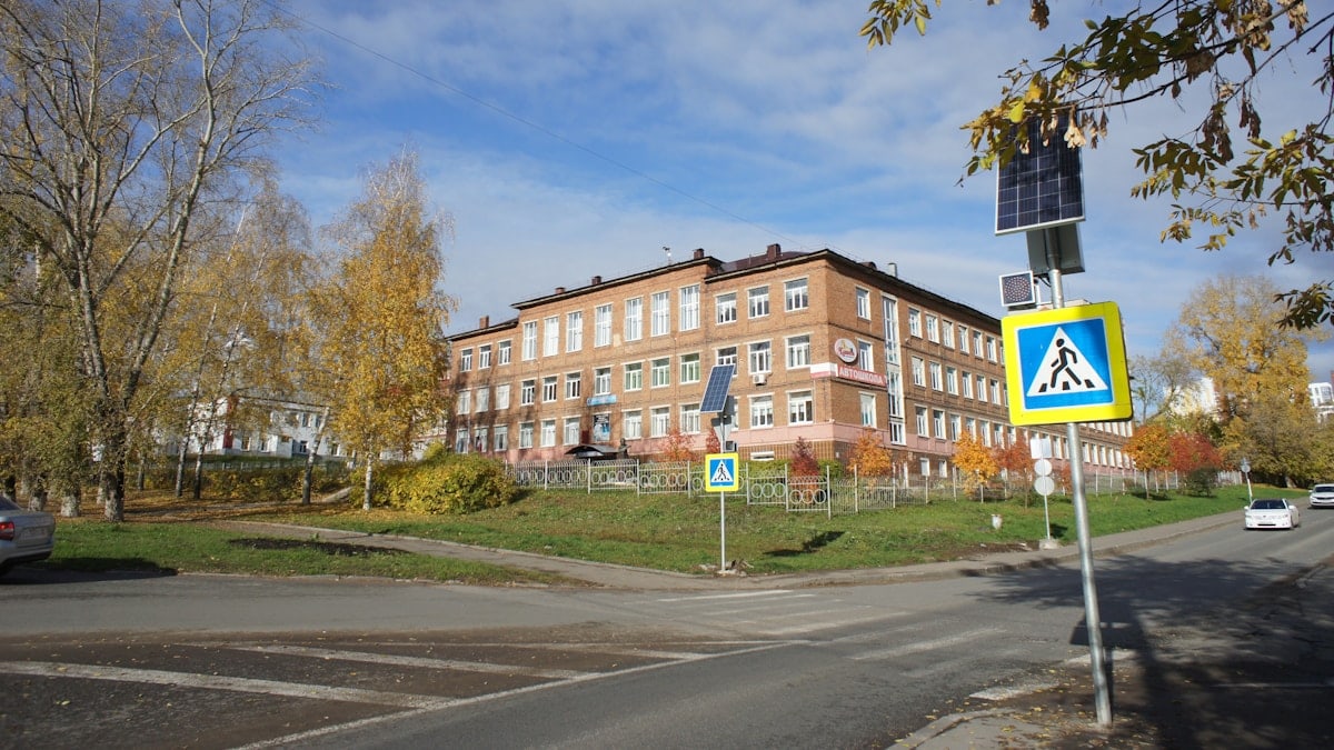 Brick building with trees in autumn near a road.